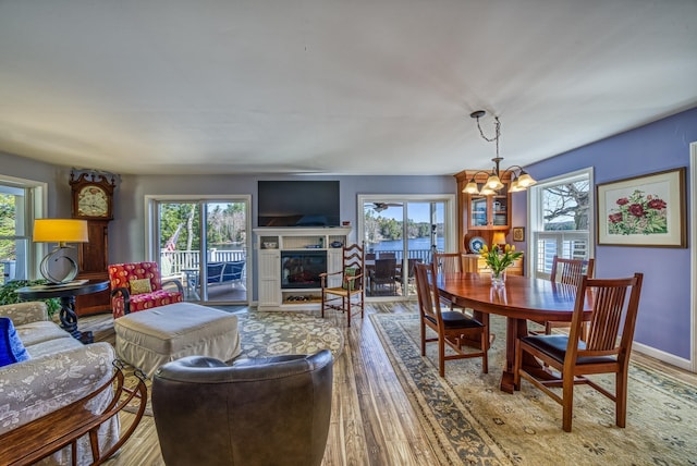 dining area featuring a glass covered fireplace, wood finished floors, and a chandelier