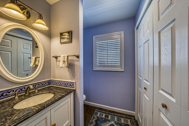 half bathroom with toilet, baseboards, and vanity