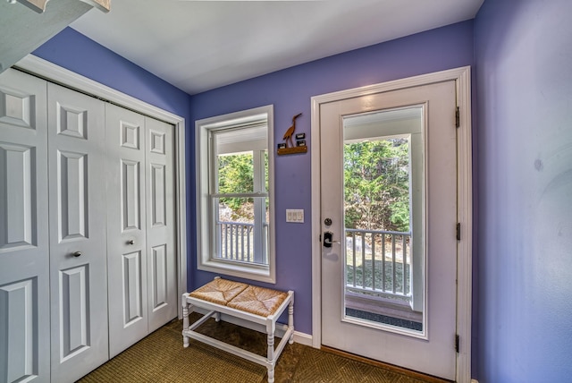 entryway with baseboards and carpet flooring