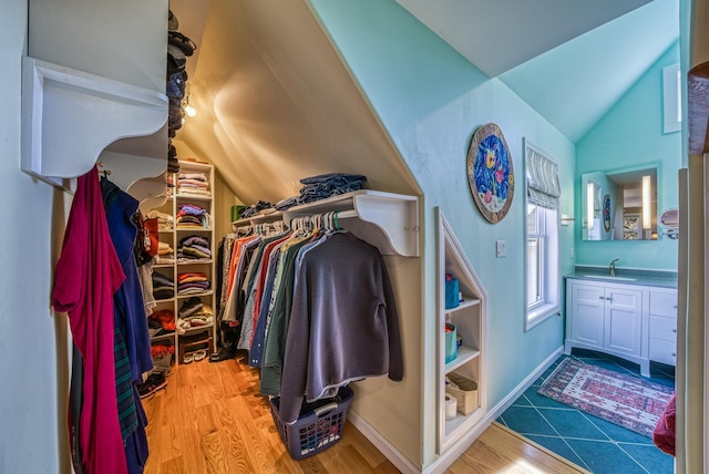 walk in closet featuring a sink, wood finished floors, and vaulted ceiling