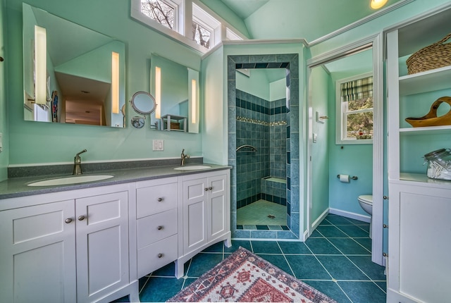 bathroom featuring a tile shower, a sink, and a healthy amount of sunlight