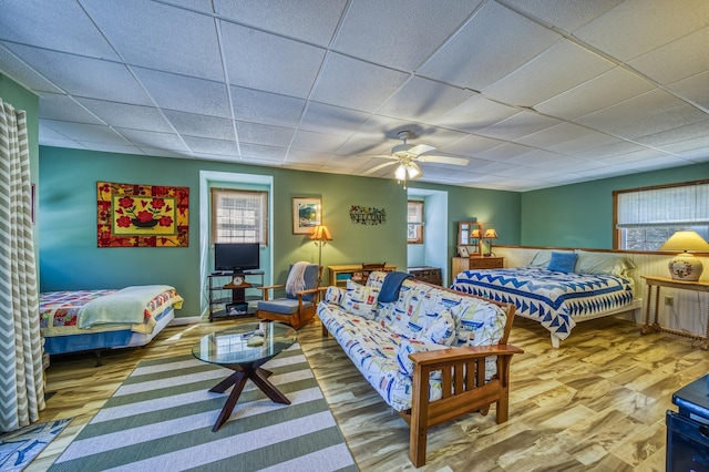 bedroom featuring a drop ceiling, multiple windows, and wood finished floors