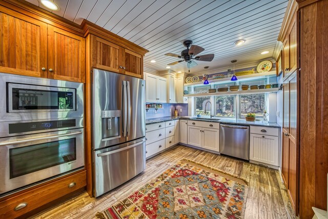 kitchen featuring brown cabinetry, a ceiling fan, a sink, light wood-style flooring, and stainless steel appliances