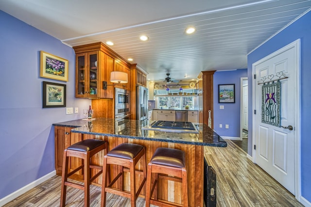 kitchen with glass insert cabinets, appliances with stainless steel finishes, baseboards, and brown cabinets