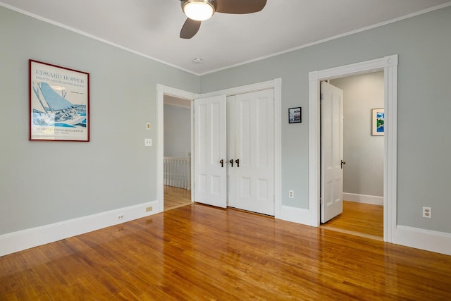 unfurnished bedroom featuring crown molding, baseboards, a closet, and wood finished floors