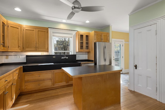 kitchen with freestanding refrigerator, backsplash, dark countertops, and glass insert cabinets