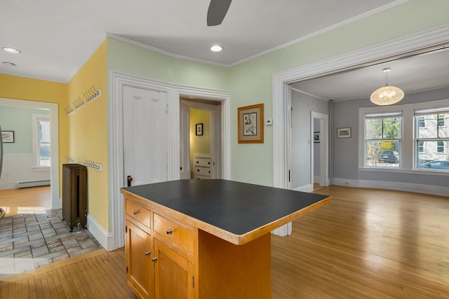 kitchen with dark countertops, baseboard heating, light wood-style flooring, a center island, and baseboards