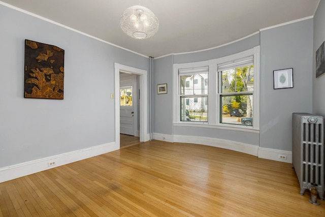 interior space featuring crown molding, baseboards, light wood finished floors, and radiator