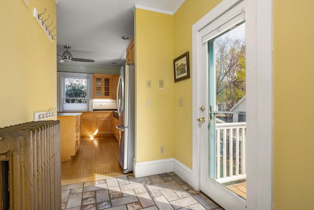 doorway to outside with stone tile flooring, ornamental molding, baseboards, and a healthy amount of sunlight