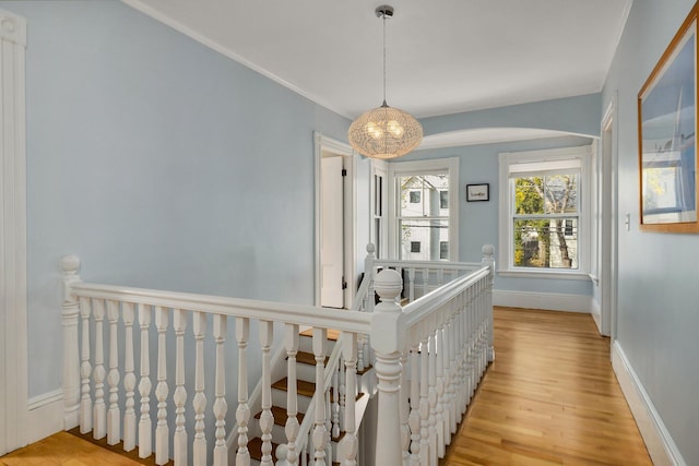 hall featuring baseboards, light wood-type flooring, and an upstairs landing