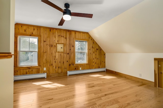 additional living space with plenty of natural light, baseboard heating, and wood finished floors
