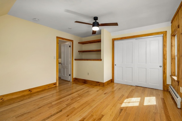 unfurnished bedroom with ceiling fan, light wood-style flooring, baseboards, a baseboard heating unit, and a closet