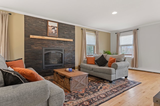 living area with crown molding, baseboards, a stone fireplace, and wood finished floors
