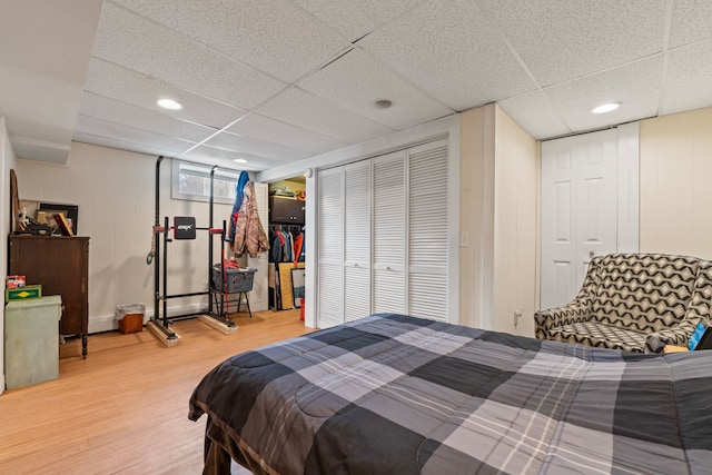 bedroom with a drop ceiling and wood finished floors