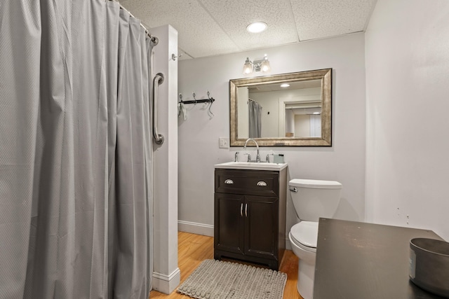 full bath featuring vanity, wood finished floors, toilet, a shower with shower curtain, and a paneled ceiling