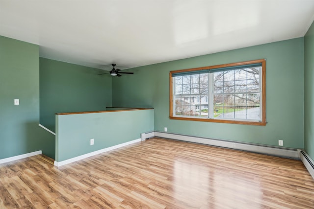 unfurnished room featuring baseboards, a ceiling fan, a baseboard heating unit, and wood finished floors