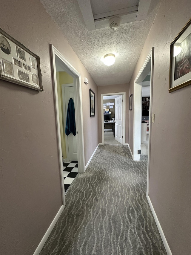hall with a textured ceiling and baseboards