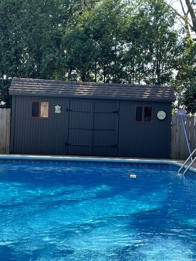 view of pool with a storage unit, fence, an outbuilding, and a fenced in pool