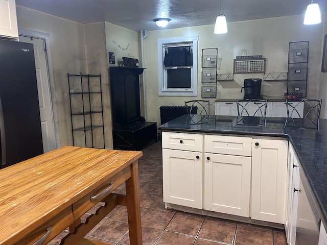 kitchen featuring dark tile patterned flooring, white cabinets, pendant lighting, and radiator