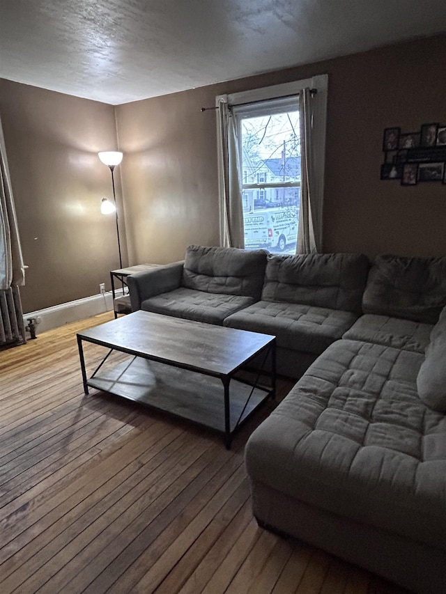 living area with baseboards, a textured ceiling, and hardwood / wood-style floors