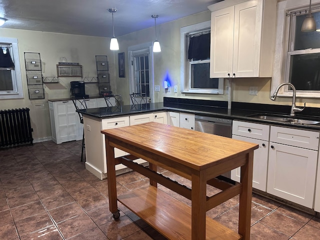kitchen with a peninsula, dark countertops, radiator heating unit, white cabinetry, and a sink