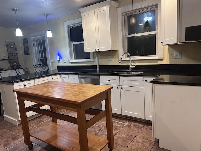 kitchen with a peninsula, dark countertops, dark tile patterned floors, white cabinetry, and a sink