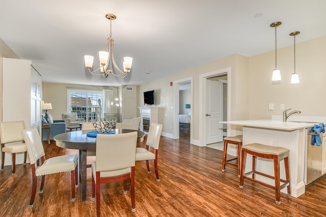 dining room featuring baseboards, a notable chandelier, a fireplace, and dark wood-style floors