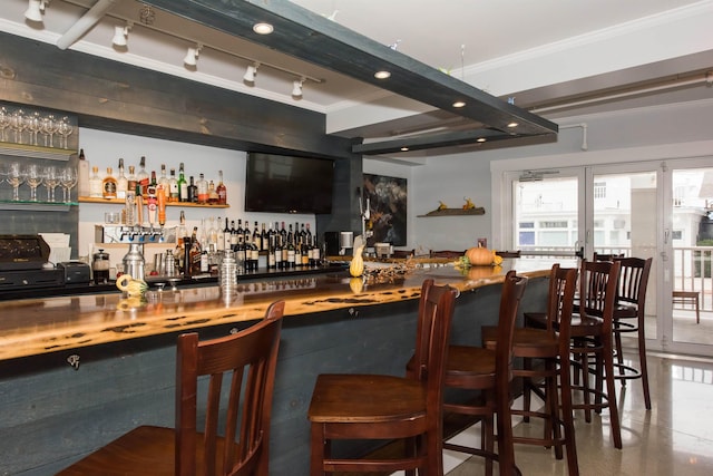 bar with a bar, rail lighting, and crown molding