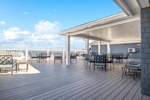 wooden deck with a water view and outdoor dining space