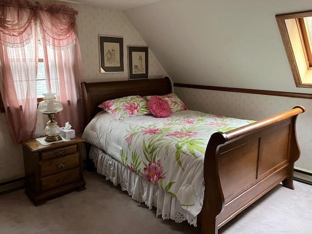 bedroom with wallpapered walls, vaulted ceiling, and light carpet