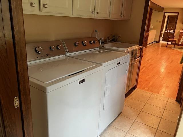 washroom with a sink, cabinet space, washing machine and dryer, and light tile patterned flooring
