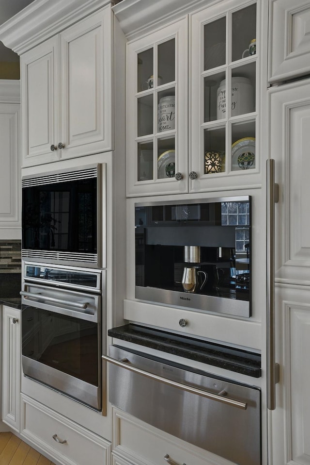 7 Champagne Ter, Bedford, NH 03110 - kitchen featuring dark countertops, glass insert cabinets, white cabinetry, built in microwave, and a warming drawer