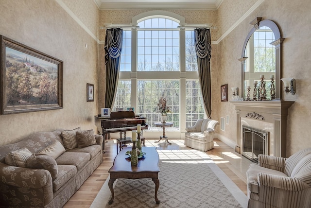 7 Champagne Ter, Bedford, NH 03110 - living area featuring a glass covered fireplace, baseboards, wood finished floors, a towering ceiling, and ornamental molding