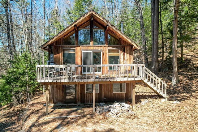 back of house with board and batten siding, a wooden deck, and stairway