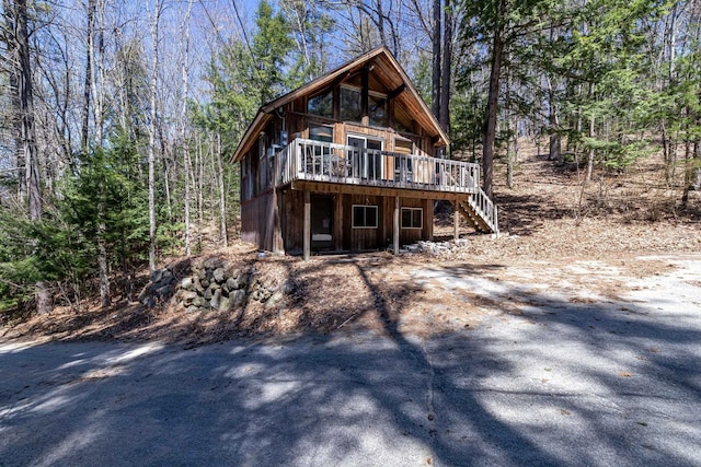 view of front of property with stairway, a deck, and a wooded view