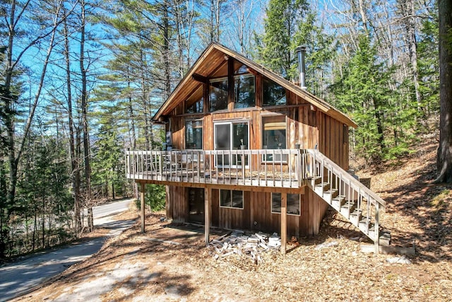 back of property featuring stairs and a deck