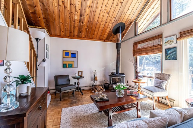 living room featuring baseboard heating, a wood stove, stairs, vaulted ceiling, and wood ceiling