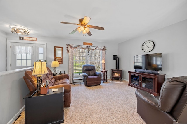 living room featuring a ceiling fan, carpet, a healthy amount of sunlight, and a wood stove