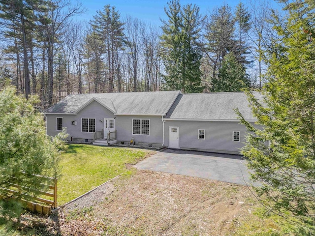 view of front of home featuring dirt driveway, a shingled roof, and a front lawn