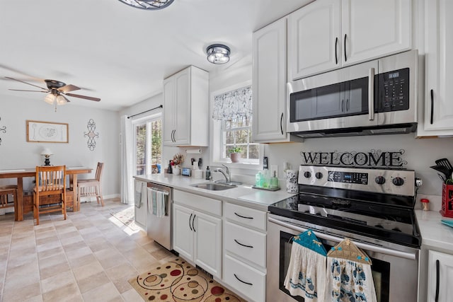 kitchen with white cabinets, a sink, light countertops, stainless steel appliances, and a ceiling fan