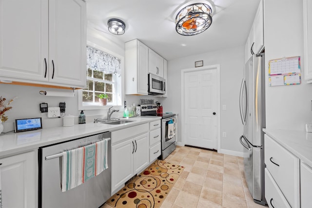 kitchen featuring baseboards, a sink, appliances with stainless steel finishes, and white cabinets