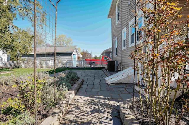 view of yard with fence, central AC unit, and a patio area