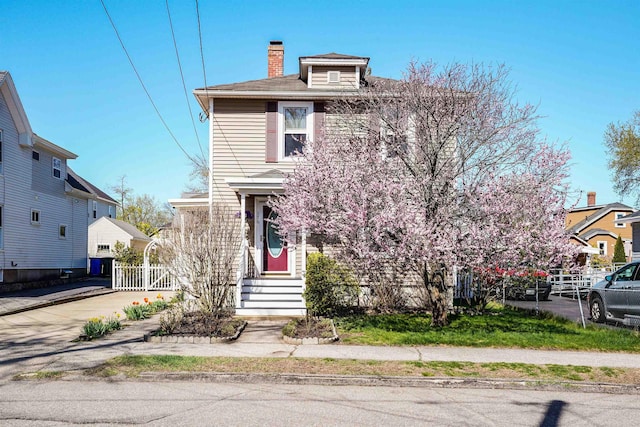american foursquare style home featuring fence and a chimney