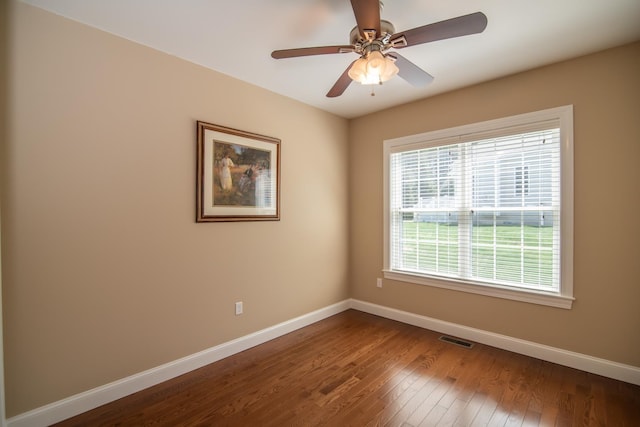 unfurnished room with a ceiling fan, baseboards, visible vents, and dark wood-style floors