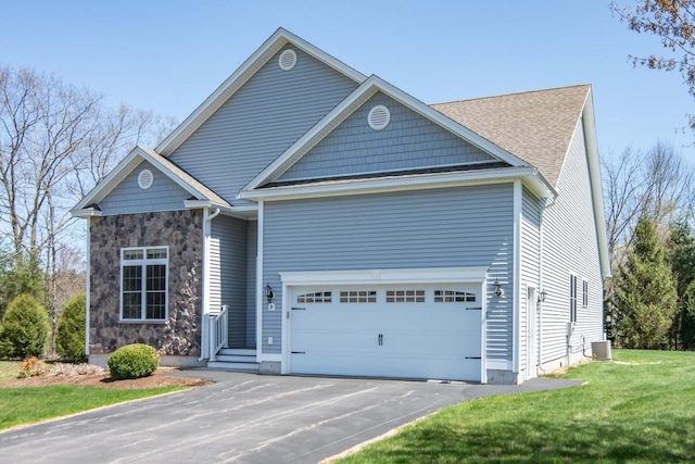view of front of home featuring stone siding, a garage, aphalt driveway, a front yard, and central AC unit