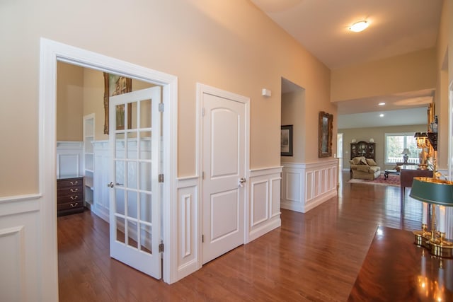 corridor featuring wainscoting, a decorative wall, and wood finished floors