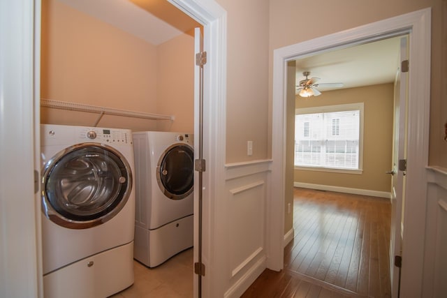 clothes washing area with laundry area, a ceiling fan, hardwood / wood-style flooring, baseboards, and separate washer and dryer