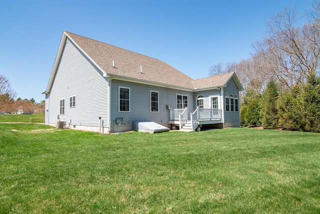 rear view of property featuring roof with shingles, a yard, a deck, and cooling unit