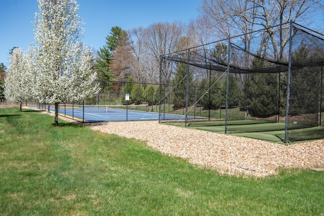 view of community with a yard, a tennis court, and fence