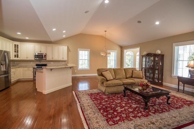 living area with baseboards, vaulted ceiling, dark wood-style floors, and a healthy amount of sunlight